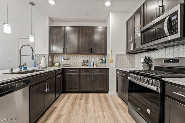 3641 Portici Ln, Henderson, NV 89044 - kitchen with stainless steel appliances, dark brown cabinets, light wood-type flooring, decorative backsplash, and recessed lighting