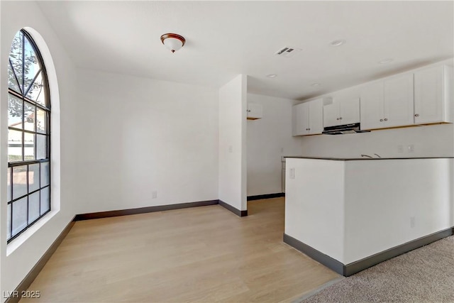 2963 Juniper Hills Blvd Unit 104, Las Vegas, NV 89142 - kitchen featuring white cabinets, light wood-style floors, and extractor fan