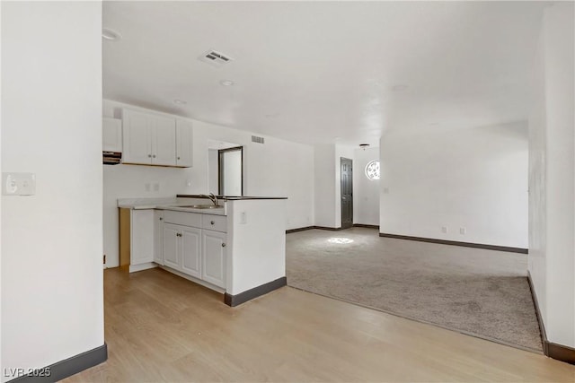 2963 Juniper Hills Blvd Unit 104, Las Vegas, NV 89142 - kitchen with white cabinetry, open floor plan, light wood-type flooring, and light colored carpet