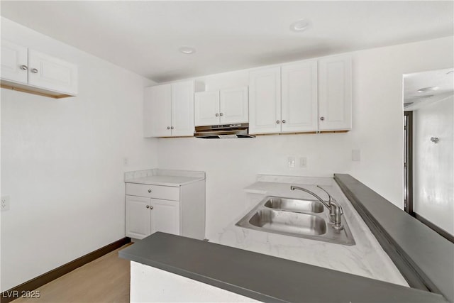 2963 Juniper Hills Blvd Unit 104, Las Vegas, NV 89142 - kitchen featuring under cabinet range hood, white cabinets, light wood-type flooring, and a peninsula