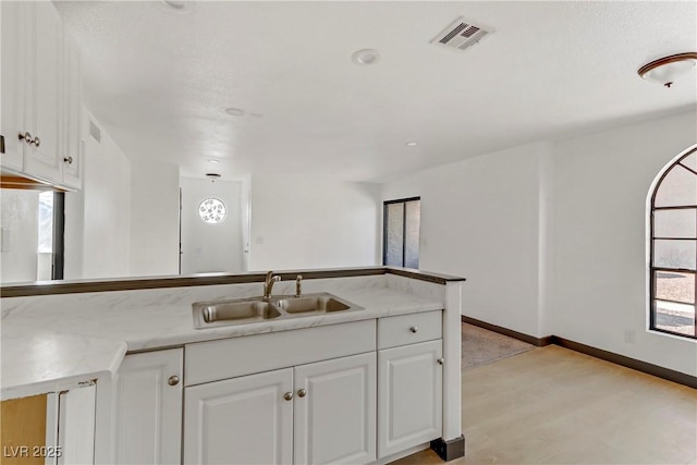 2963 Juniper Hills Blvd Unit 104, Las Vegas, NV 89142 - kitchen with white cabinets, light wood-style floors, light countertops, and a peninsula