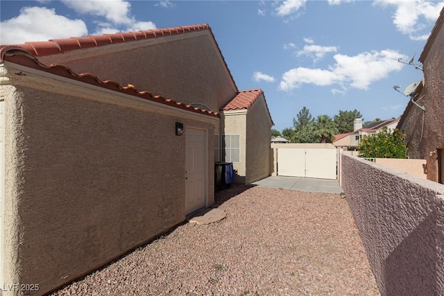 426 Lost Trail Dr, Henderson, NV 89014 - view of side of home featuring a gate, stucco siding, and a tiled roof