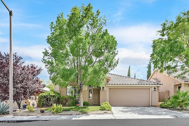 9517 Mountainair Ave, Las Vegas, NV 89134 - view of property hidden behind natural elements featuring an attached garage, stucco siding, a tiled roof, and driveway