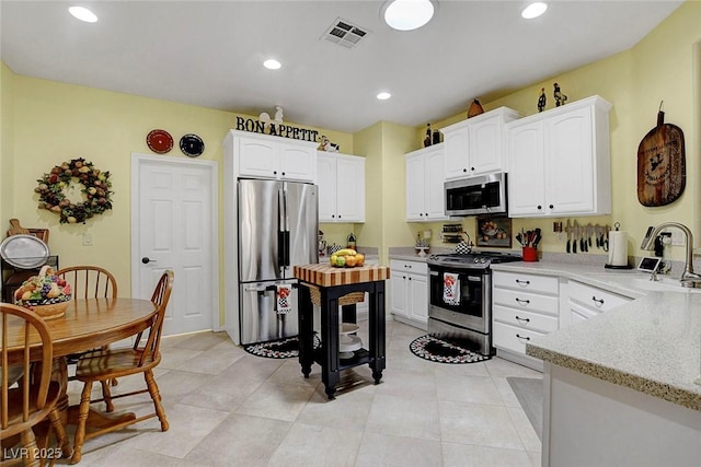 169 Pioneer Peak Pl, Las Vegas, NV 89138 - kitchen with stainless steel appliances, white cabinetry, light stone countertops, recessed lighting, and light tile patterned floors