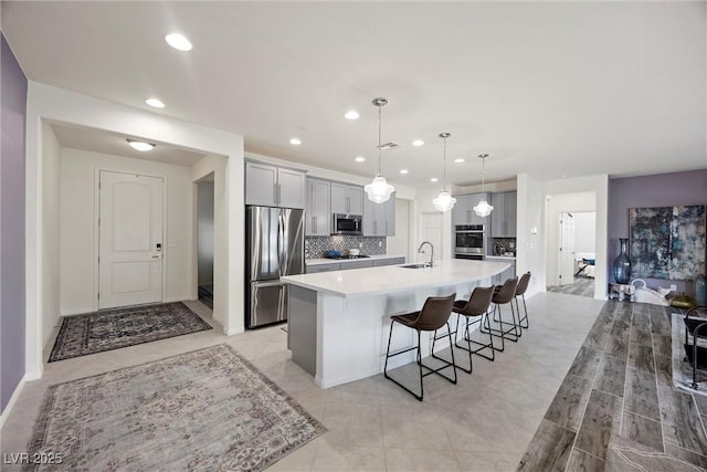 605 Cadence Vista Dr, Henderson, NV 89011 - kitchen featuring appliances with stainless steel finishes, light countertops, a large island with sink, recessed lighting, and tasteful backsplash
