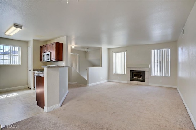 2801 N Rainbow Blvd Unit 273, Las Vegas, NV 89108 - kitchen with stainless steel microwave, light carpet, ceiling fan, and a tiled fireplace
