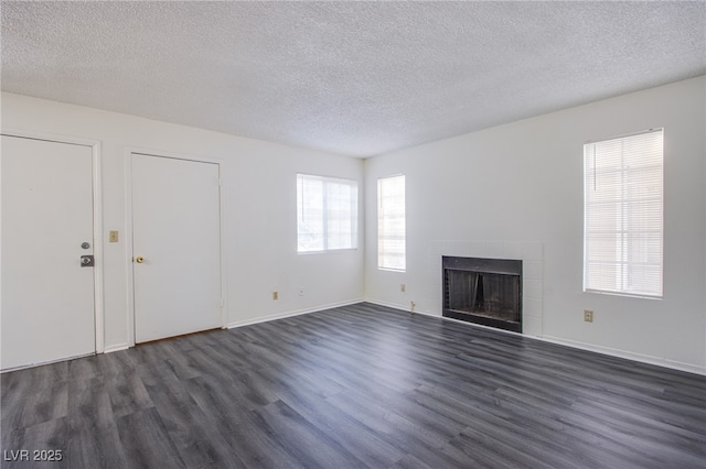 2696 Jennydiane Dr, Las Vegas, NV 89121 - unfurnished living room with dark wood-type flooring, a tiled fireplace, and a textured ceiling