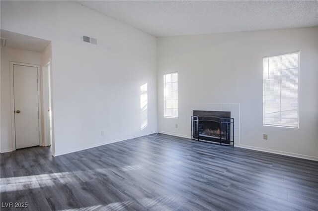 2696 Jennydiane Dr, Las Vegas, NV 89121 - unfurnished living room featuring vaulted ceiling, dark wood-type flooring, a tiled fireplace, and a textured ceiling