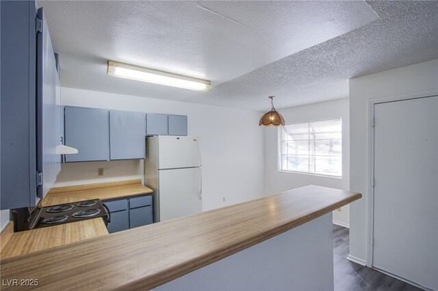2696 Jennydiane Dr, Las Vegas, NV 89121 - kitchen with freestanding refrigerator, a textured ceiling, butcher block countertops, blue cabinets, and dark wood finished floors
