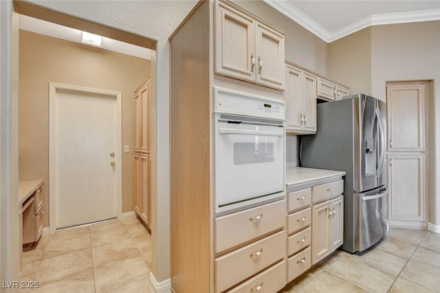 1904 Hot Oak Ridge St, Las Vegas, NV 89134 - kitchen with white oven, stainless steel refrigerator with ice dispenser, ornamental molding, light tile patterned flooring, and light countertops
