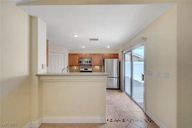 4841 Raw Umber Ct, Las Vegas, NV 89131 - kitchen featuring appliances with stainless steel finishes, backsplash, a peninsula, light tile patterned flooring, and light countertops