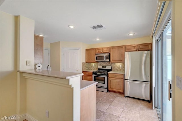 4841 Raw Umber Ct, Las Vegas, NV 89131 - kitchen with stainless steel appliances, light countertops, backsplash, a peninsula, and brown cabinetry