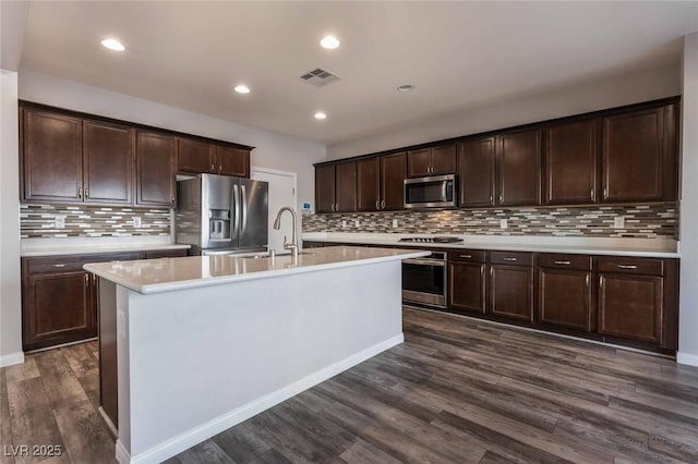 9850 Poplar Point Ave, Las Vegas, NV 89178 - kitchen featuring appliances with stainless steel finishes, light countertops, dark brown cabinetry, decorative backsplash, and dark wood-style flooring