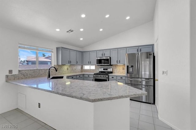1613 Glenrosa Dr, North Las Vegas, NV 89031 - kitchen with appliances with stainless steel finishes, a peninsula, gray cabinetry, decorative backsplash, and light tile patterned flooring