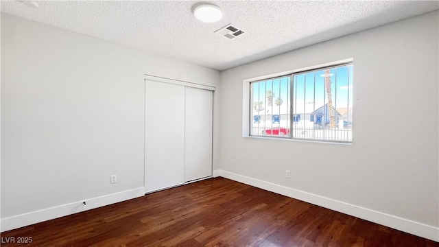 744 Hubbard St, Las Vegas, NV 89110 - unfurnished bedroom featuring dark wood-style flooring, a textured ceiling, and a closet