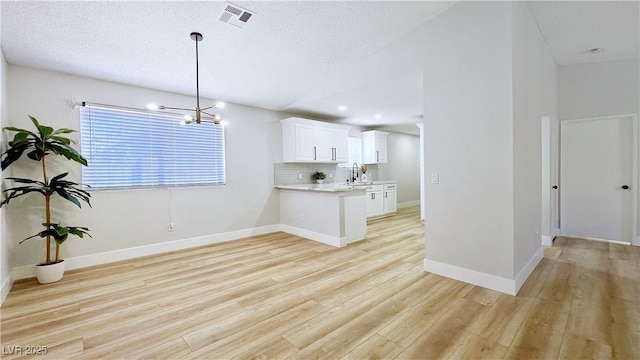 744 Hubbard St, Las Vegas, NV 89110 - kitchen featuring light wood-style flooring, light countertops, backsplash, a chandelier, and white cabinetry