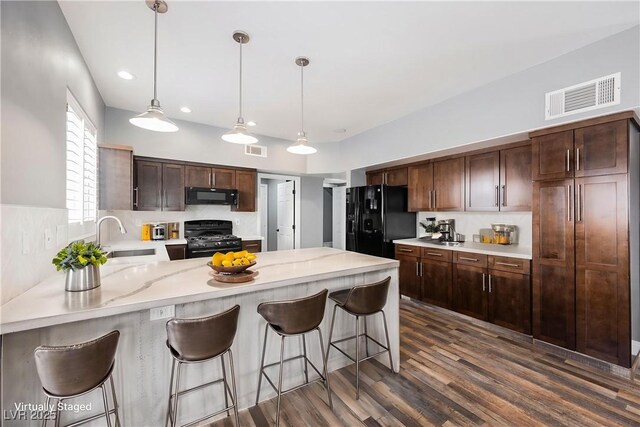 209 Camino Vista St, Henderson, NV 89012 - kitchen with black appliances, a peninsula, dark wood-style flooring, decorative light fixtures, and dark brown cabinetry