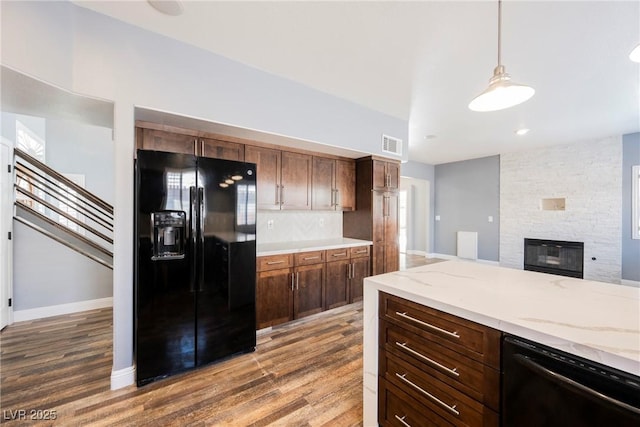209 Camino Vista St, Henderson, NV 89012 - kitchen with black appliances, a fireplace, wood finished floors, and light stone countertops