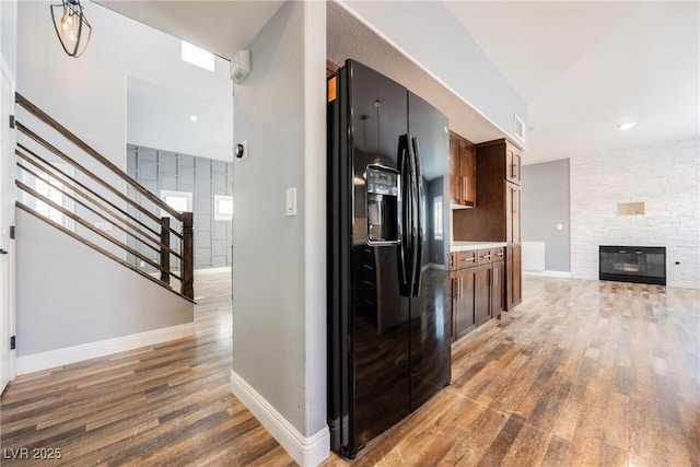 209 Camino Vista St, Henderson, NV 89012 - kitchen with black refrigerator with ice dispenser, light wood-style flooring, a stone fireplace, light countertops, and open floor plan