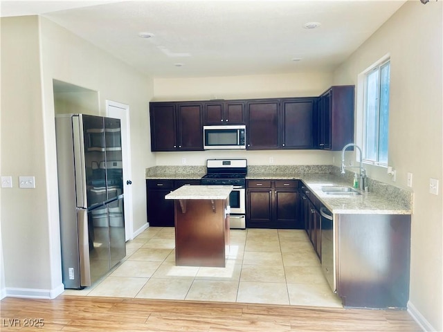 6043 Cape Clairmont Ct, North Las Vegas, NV 89031 - kitchen with appliances with stainless steel finishes, a kitchen island, light stone countertops, and light wood-style floors