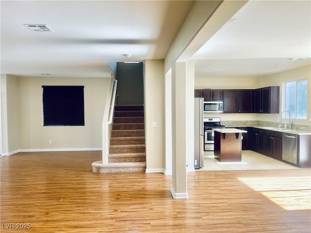 6043 Cape Clairmont Ct, North Las Vegas, NV 89031 - kitchen with appliances with stainless steel finishes, open floor plan, light wood-style floors, light countertops, and a kitchen bar