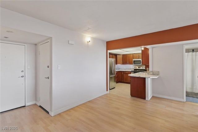 3930 University Center Dr Unit 804, Las Vegas, NV 89119 - kitchen featuring stainless steel appliances, brown cabinetry, a peninsula, and light wood-style floors