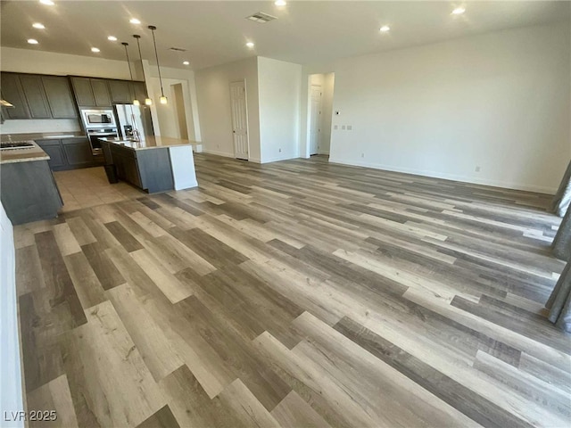 8550 Lost Pony St, Las Vegas, NV 89148 - kitchen featuring appliances with stainless steel finishes, open floor plan, a center island with sink, light wood-type flooring, and light countertops