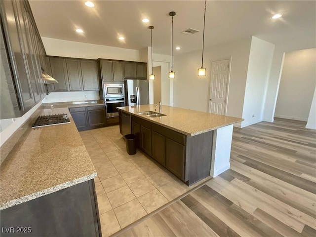 8550 Lost Pony St, Las Vegas, NV 89148 - kitchen with stainless steel appliances, light wood-style flooring, a kitchen island with sink, dark brown cabinets, and recessed lighting