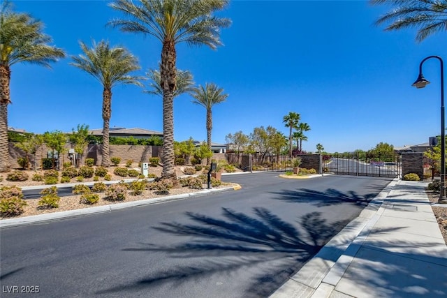 8550 Lost Pony St, Las Vegas, NV 89148 - view of asphalt road with a gate, sidewalks, curbs, and street lights
