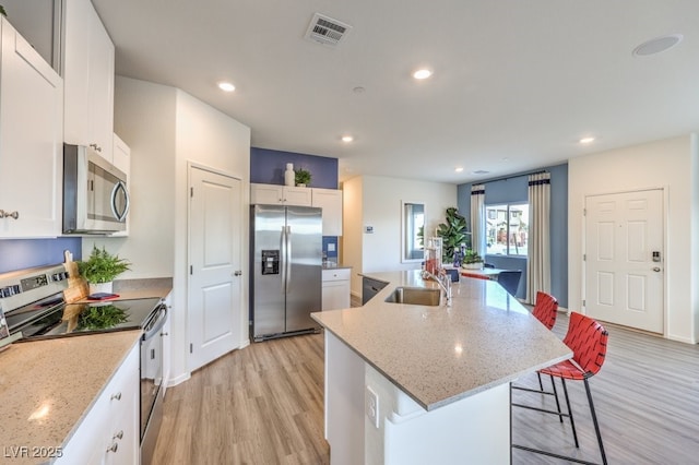 7965 Aurora Sky St Unit 623, North Las Vegas, NV 89084 - kitchen with stainless steel appliances, light wood-style flooring, an island with sink, recessed lighting, and white cabinets