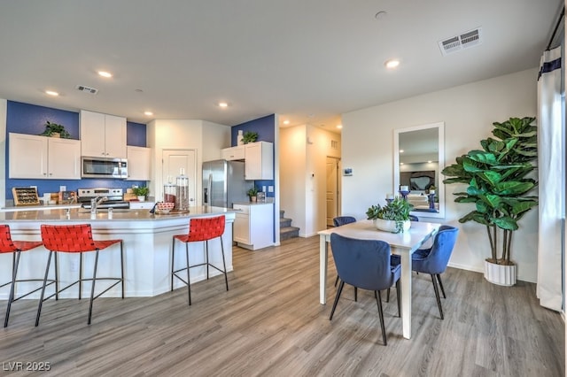 7965 Aurora Sky St Unit 623, North Las Vegas, NV 89084 - kitchen with stainless steel appliances, light wood-style floors, a kitchen bar, white cabinets, and recessed lighting
