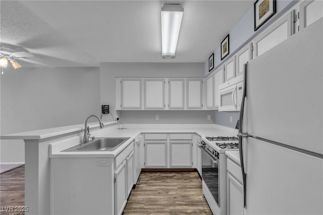 2124 Willowbury Dr Unit D, Las Vegas, NV 89108 - kitchen featuring white appliances, a peninsula, a ceiling fan, dark wood-type flooring, and white cabinetry