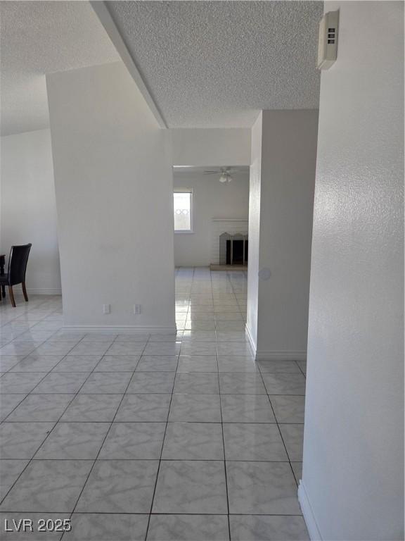 6402 Agua Dr, Las Vegas, NV 89103 - empty room with a textured ceiling, a brick fireplace, a ceiling fan, and light tile patterned floors