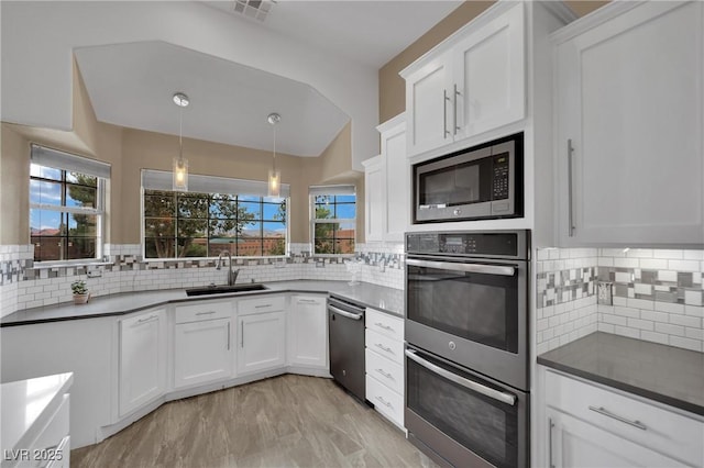 9180 Mohawk St, Las Vegas, NV 89139 - kitchen with stainless steel appliances, backsplash, white cabinets, hanging light fixtures, and lofted ceiling