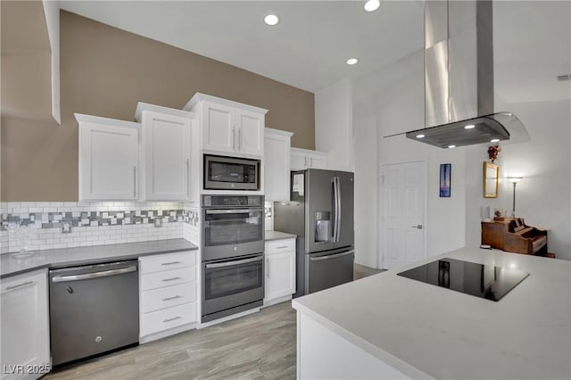 9180 Mohawk St, Las Vegas, NV 89139 - kitchen with appliances with stainless steel finishes, island range hood, backsplash, white cabinets, and light wood-style flooring
