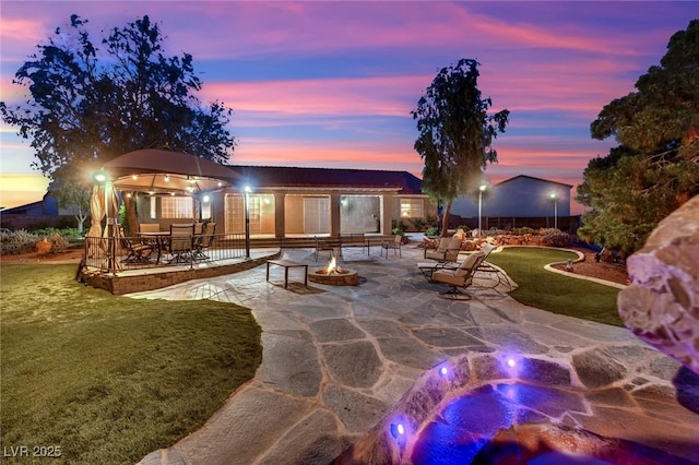 9180 Mohawk St, Las Vegas, NV 89139 - patio terrace at dusk with a fire pit, a patio, and a yard