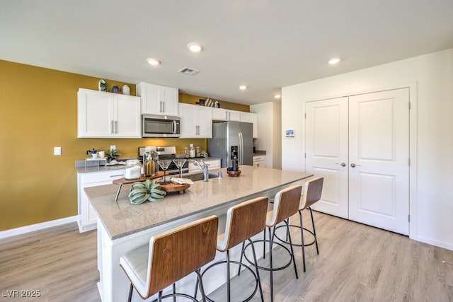 5702 Sunset Sedona St Lot 2, North Las Vegas, NV 89081 - kitchen with appliances with stainless steel finishes, white cabinets, light wood finished floors, a kitchen island with sink, and a kitchen breakfast bar