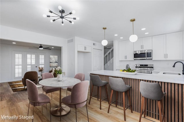 572 Tam O Shanter, Las Vegas, NV 89109 - kitchen featuring appliances with stainless steel finishes, a peninsula, light countertops, light wood-type flooring, and white cabinetry
