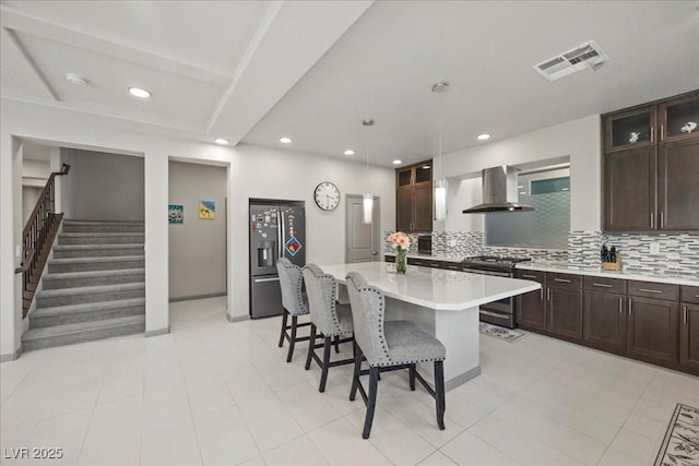 6618 Tangled Vines Ave, Las Vegas, NV 89139 - kitchen with appliances with stainless steel finishes, wall chimney exhaust hood, a breakfast bar, light countertops, and backsplash