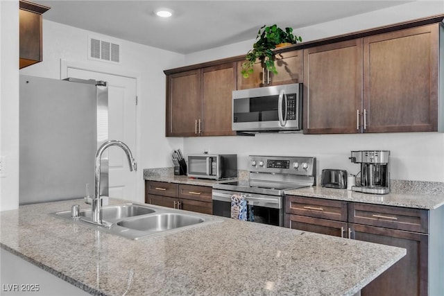 6953 Midnight Bronze St, North Las Vegas, NV 89086 - kitchen with stainless steel appliances, dark brown cabinets, and light stone countertops