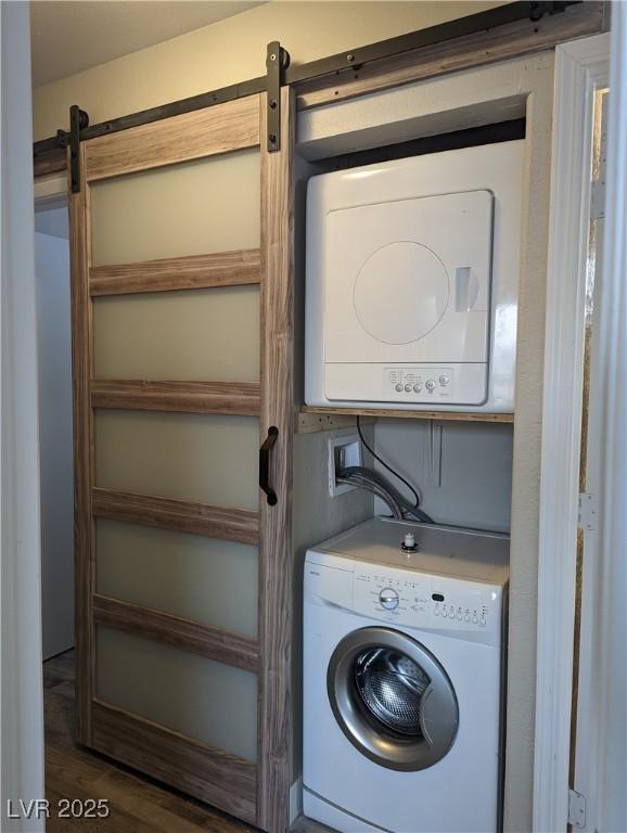 1220 Toledo St, Henderson, NV 89015 - laundry area with estacked washer and dryer, a barn door, and wood finished floors