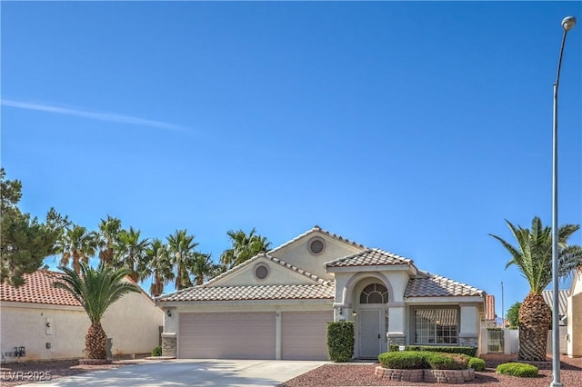 5425 Thomaston Ct, Las Vegas, NV 89122 - mediterranean / spanish home with driveway, an attached garage, a tiled roof, and stucco siding