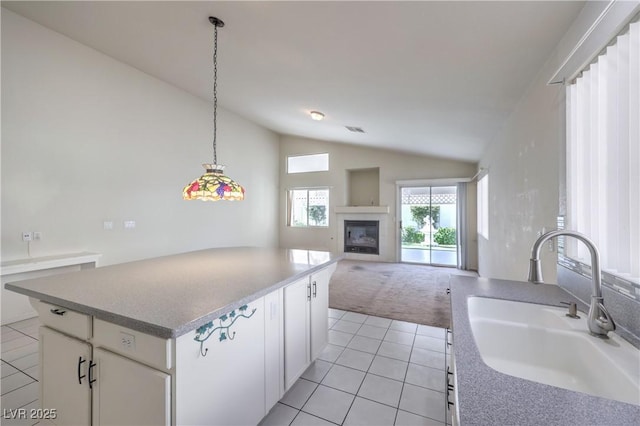 5425 Thomaston Ct, Las Vegas, NV 89122 - kitchen featuring lofted ceiling, light tile patterned flooring, a fireplace, a kitchen island, and white cabinetry