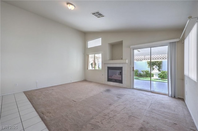 5425 Thomaston Ct, Las Vegas, NV 89122 - unfurnished living room with vaulted ceiling, plenty of natural light, a tiled fireplace, carpet, and tile patterned floors