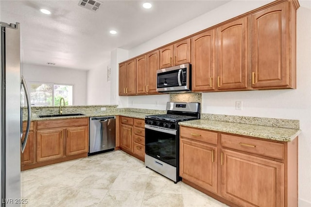 2149 Kelsey Creek Ct, Henderson, NV 89044 - kitchen with appliances with stainless steel finishes, light stone countertops, recessed lighting, and brown cabinetry