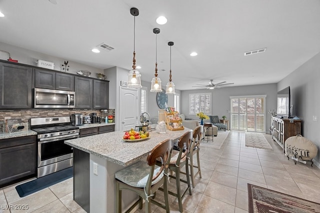 145 Langley Hill Ave, Henderson, NV 89002 - kitchen with appliances with stainless steel finishes, light tile patterned flooring, tasteful backsplash, a kitchen bar, and ceiling fan