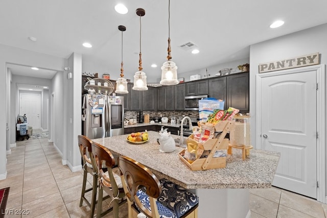 145 Langley Hill Ave, Henderson, NV 89002 - kitchen with appliances with stainless steel finishes, light tile patterned floors, tasteful backsplash, light stone countertops, and a kitchen island with sink