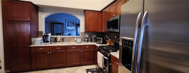 7395 Howell Mill Ct, Las Vegas, NV 89113 - kitchen with stainless steel appliances, light tile patterned floors, arched walkways, and light stone countertops