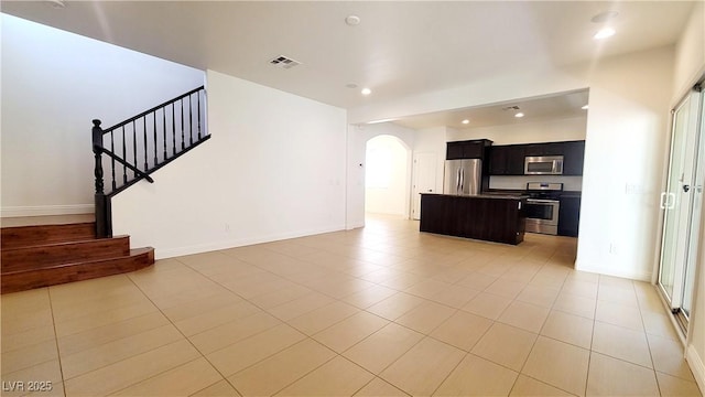 145 Forest Crossing Ct, Las Vegas, NV 89148 - unfurnished living room featuring arched walkways, recessed lighting, light tile patterned floors, and stairs