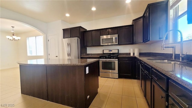 145 Forest Crossing Ct, Las Vegas, NV 89148 - kitchen featuring stainless steel appliances, dark stone countertops, arched walkways, light tile patterned floors, and a kitchen island